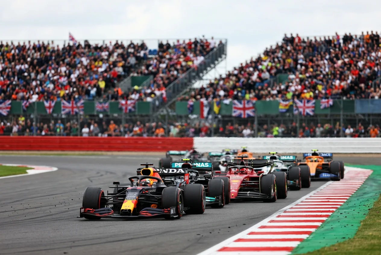 Cars approaching Copse corner at Silverstone during the British Grand Prix with a packed grandstand in the background